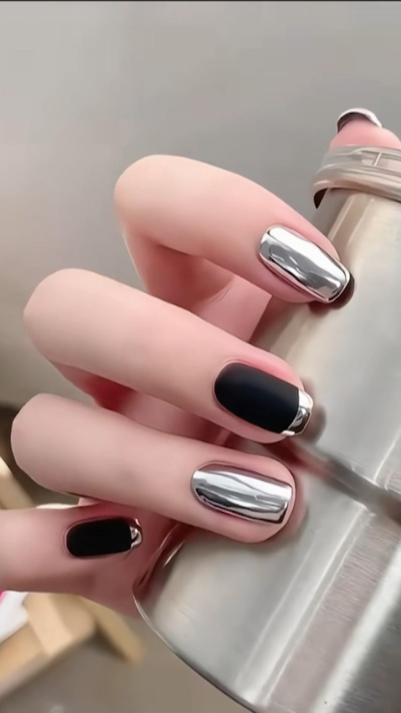 A beautiful aesthetic close-up of glossy black almond nails finished with an ultra-thin, highly reflective metallic chrome silver French smile line.