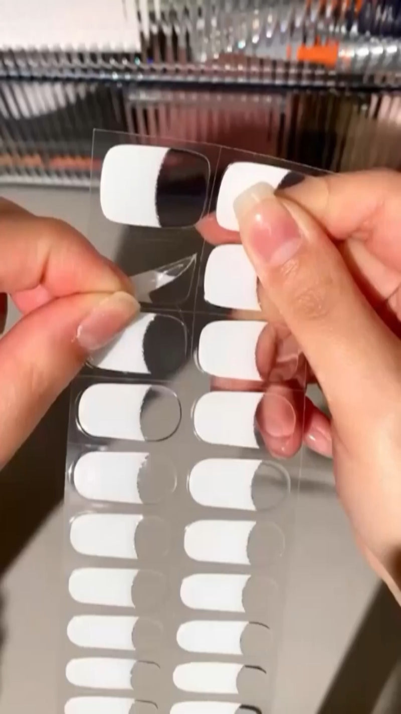 Hands smoothing a flexible, pink semi-cured gel nail sticker onto a thumb before curing under a UV lamp.