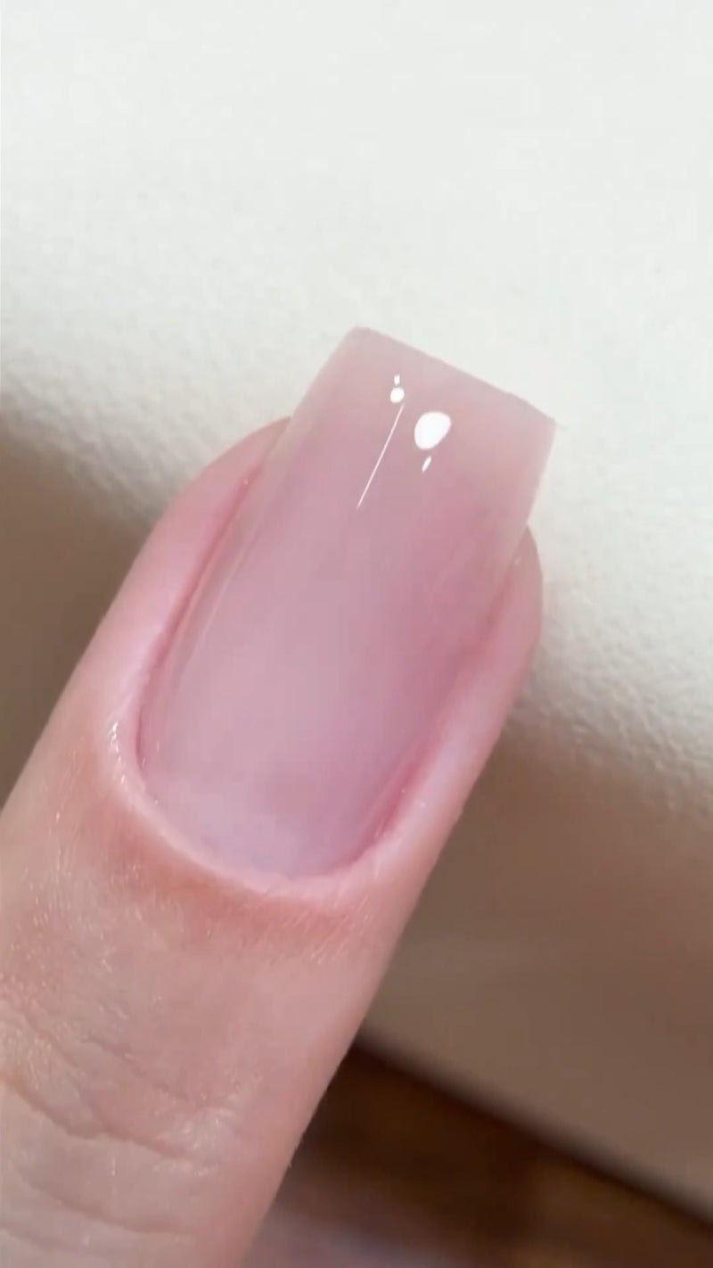 Close-up of freshly finished Soap Nails showing a sheer pink tint and a hyper-reflective, wet-look glossy top coat.