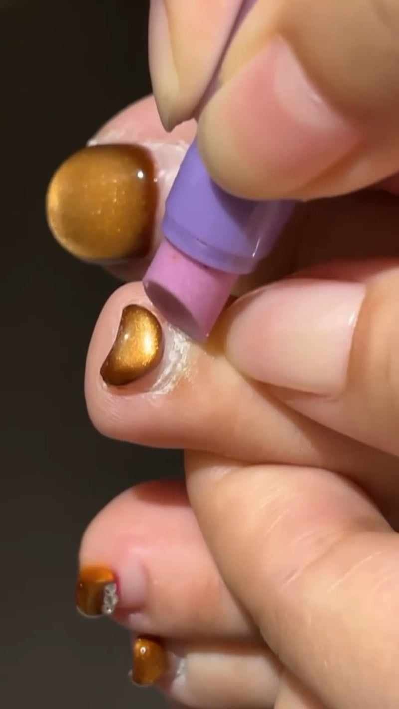 A close-up view showing a professional ceramic cuticle pen gently pushing back the cuticle line while depositing clean, clear hydrating oil.