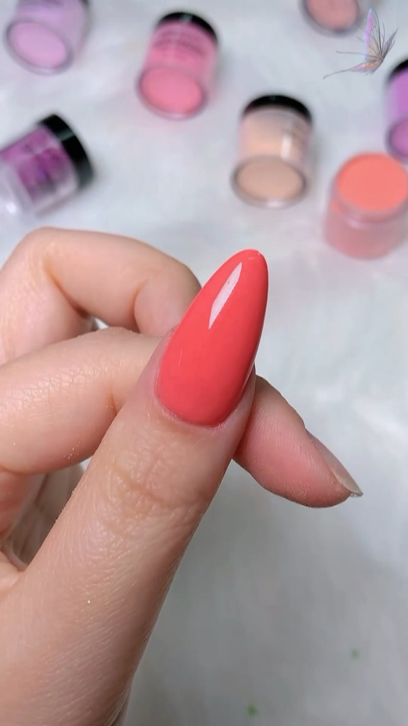 A hand dipping a finger into a small jar of pink acrylic dip powder during a home manicure tutorial.