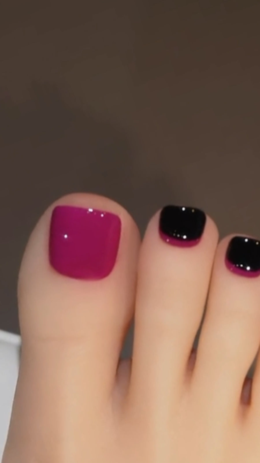 A 1:1 view of a professional pedicure showcasing an elegant retro French design on the toenails, featuring a vibrant purple base layered with a clean black gel overlay that leaves a precise curved margin around the cuticles.
